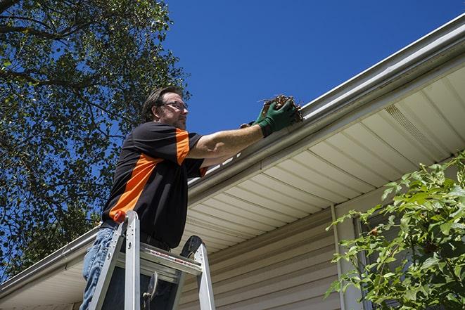 maintenance worker replacing a damaged gutter in Blythe